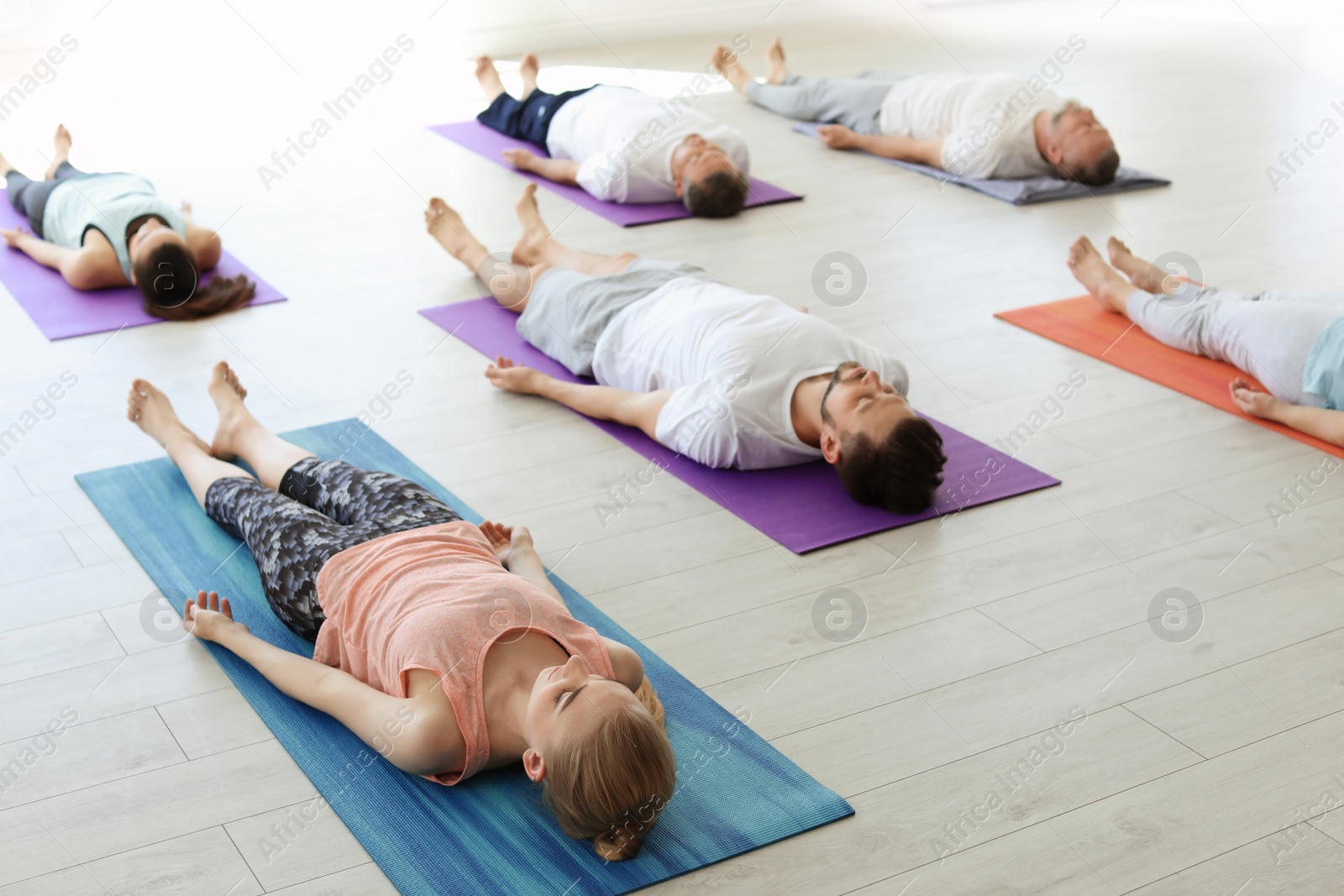 Photo of Group of people in sportswear practicing yoga indoors