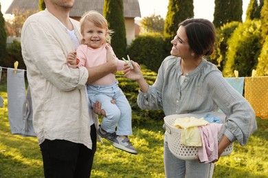 Photo of Happy family near washing line with drying clothes in backyard