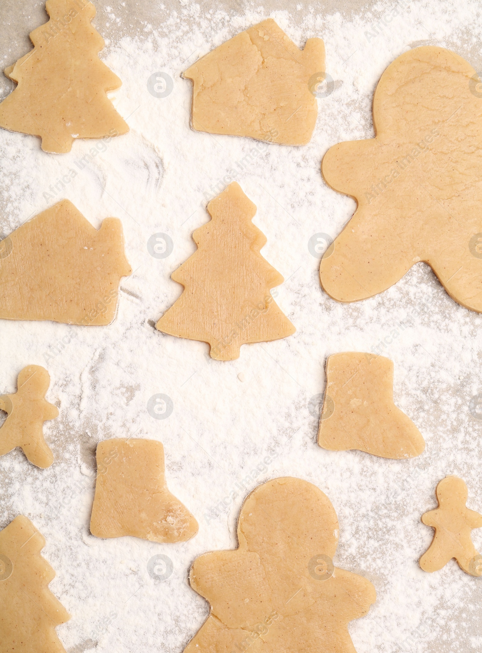 Photo of Raw Christmas cookies in different shapes on parchment paper, flat lay