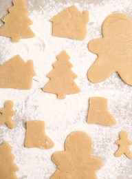 Photo of Raw Christmas cookies in different shapes on parchment paper, flat lay