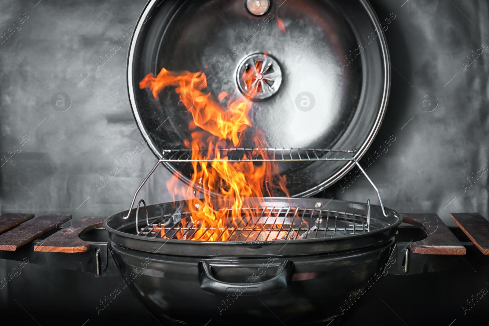 Photo of New modern barbecue grill with coals on black background