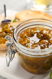 Photo of Jar with delicious gooseberry jam on table, closeup