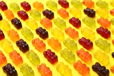 Photo of Delicious gummy bear candies on yellow background