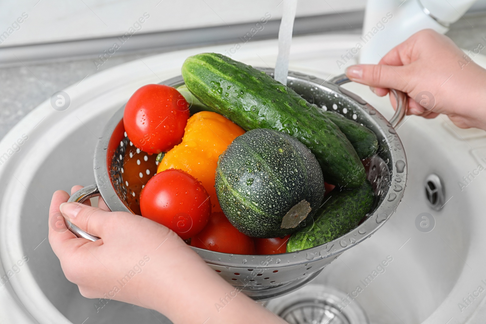 Photo of Woman washing fresh vegetables in colander under water, closeup