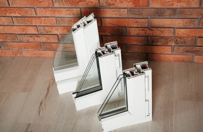 Photo of Samples of modern window profiles on floor against brick wall. Installation service