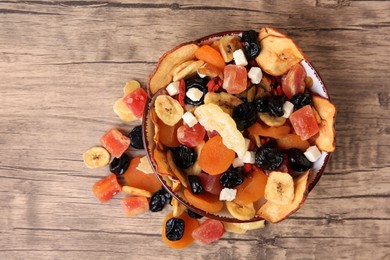 Bowl and different tasty dried fruits on wooden table, flat lay