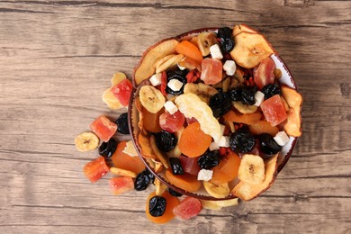 Photo of Bowl and different tasty dried fruits on wooden table, flat lay