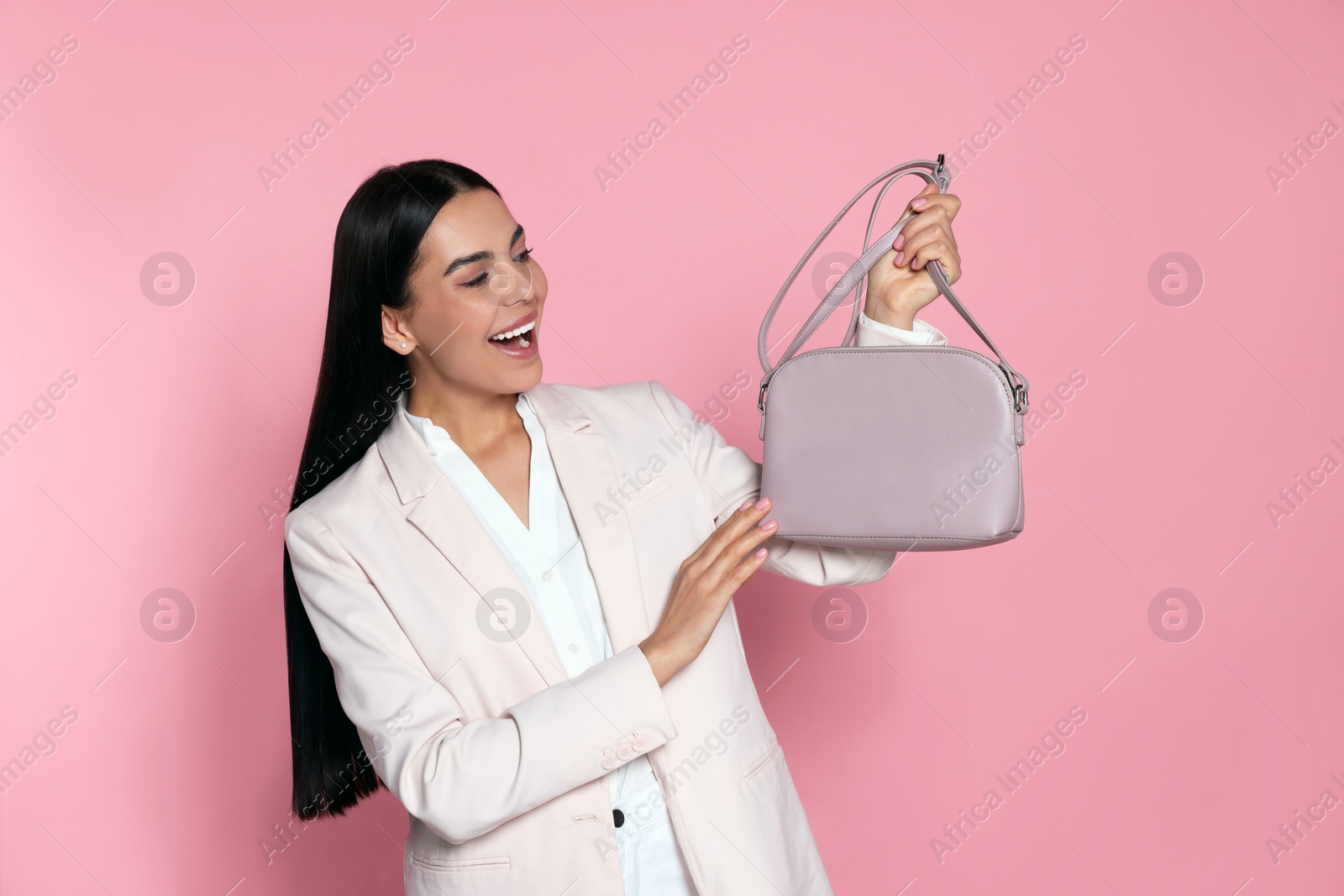 Photo of Happy young woman with stylish bag on pink background