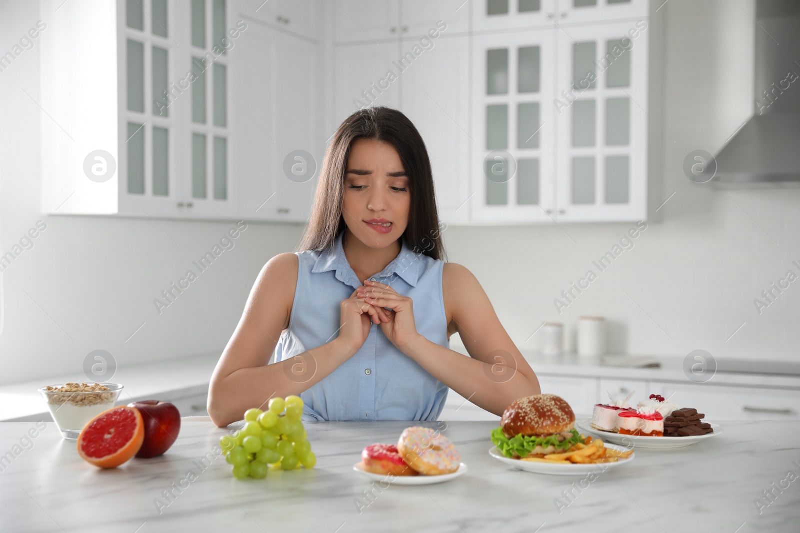 Photo of Concept of choice between healthy and junk food. Woman with products in kitchen