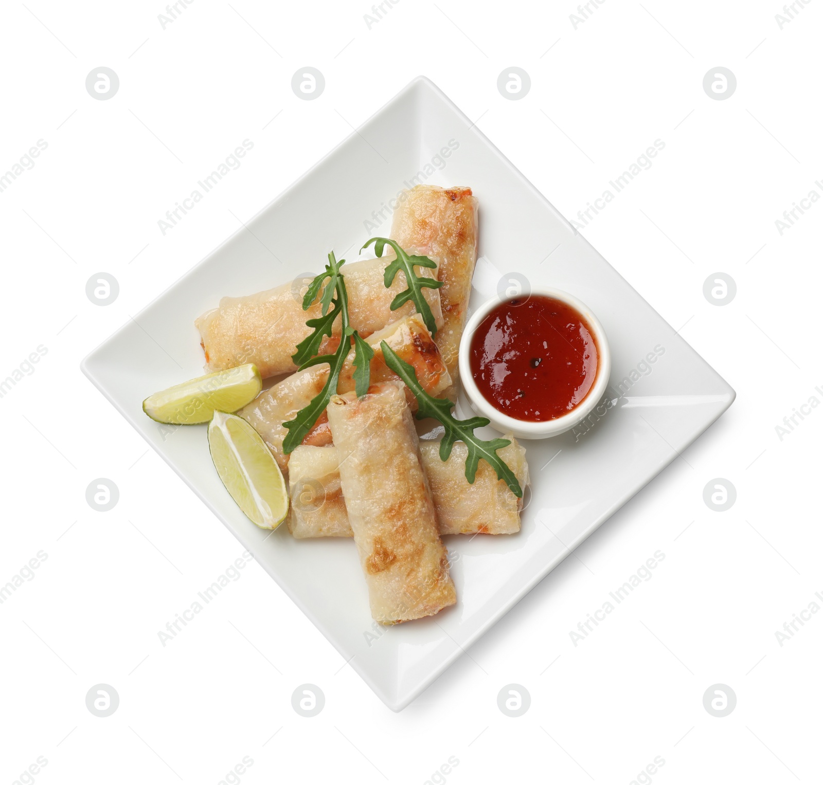 Photo of Tasty fried spring rolls, arugula, lime and sauce isolated on white, top view