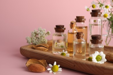 Photo of Aromatherapy. Different essential oils, flowers and almonds on pink background