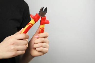 Woman with diagonal pliers on grey background, closeup. Space for text