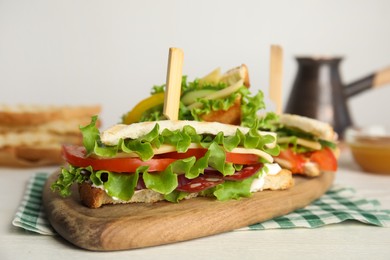 Delicious sandwiches with vegetables and cheese on white table, closeup