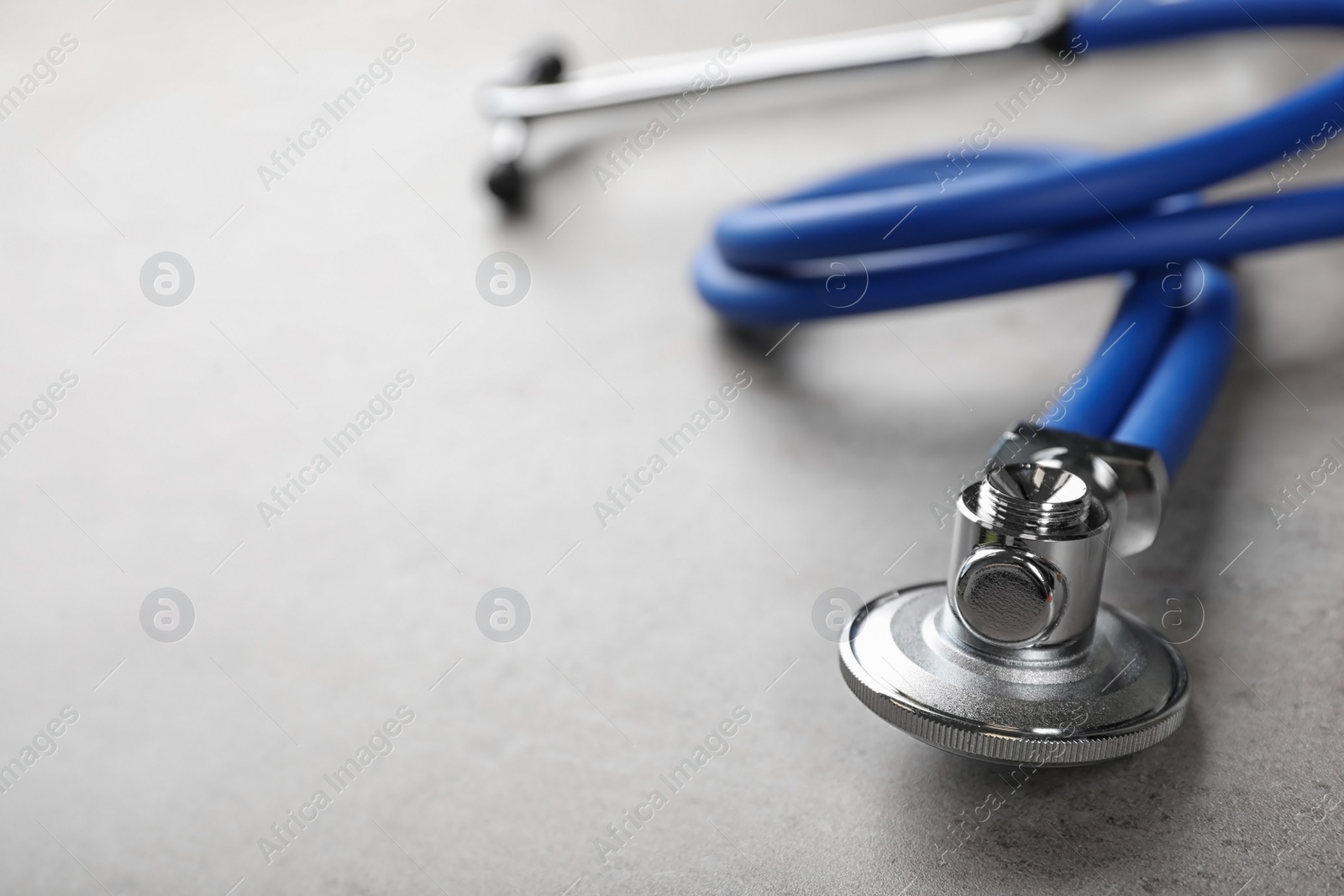 Photo of Stethoscope for checking pulse on gray table, closeup. Space for text
