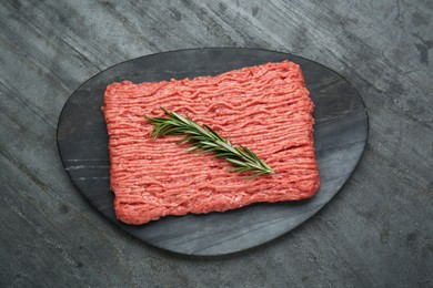 Photo of Raw fresh minced meat with rosemary on black wooden table, top view