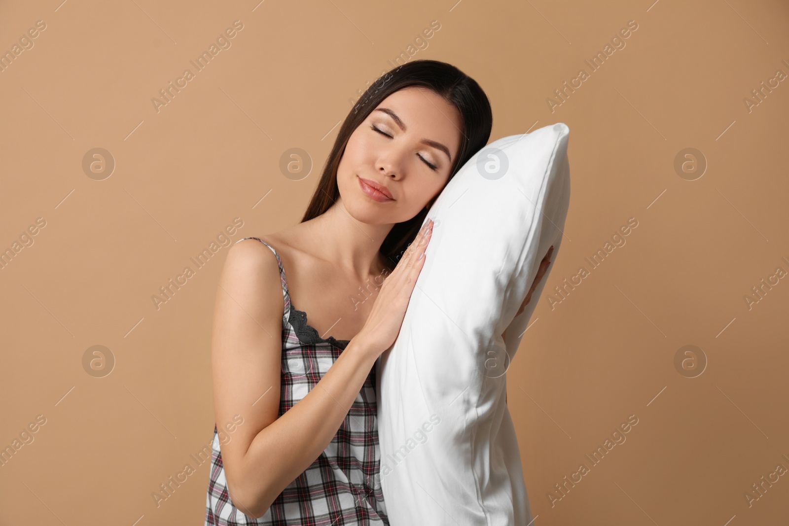 Photo of Beautiful Asian woman with pillow on beige background. Bedtime