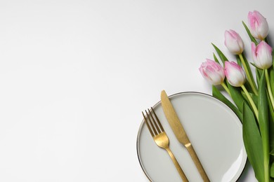 Photo of Stylish table setting with cutlery and tulips on white background, flat lay. Space for text