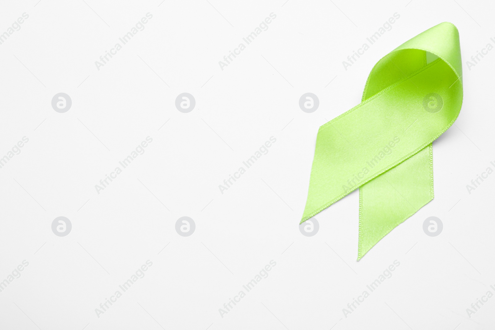 Photo of World Mental Health Day. Green ribbon on white background, top view with space for text