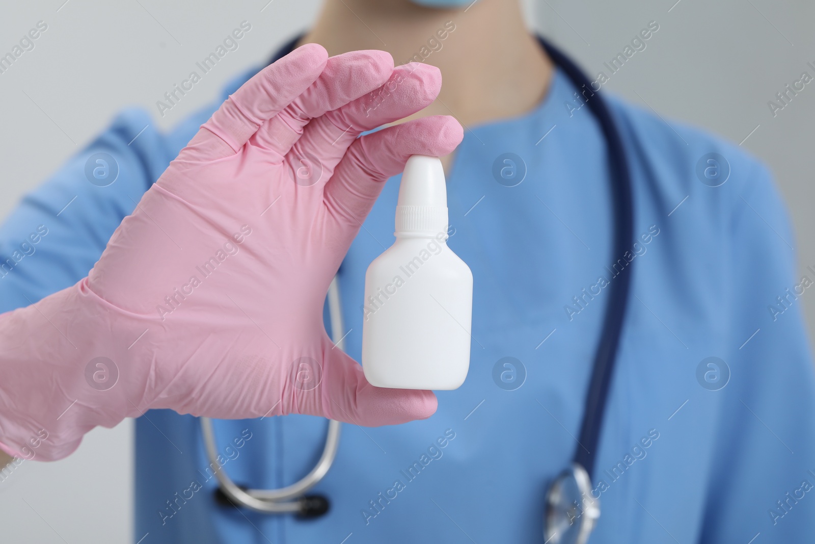 Photo of Doctor holding nasal spray on white background, closeup