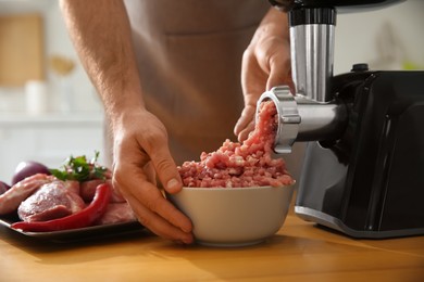 Photo of Man using modern meat grinder in kitchen, closeup
