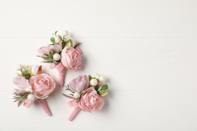 Photo of Beautiful boutonnieres on white background, flat lay. Space for text