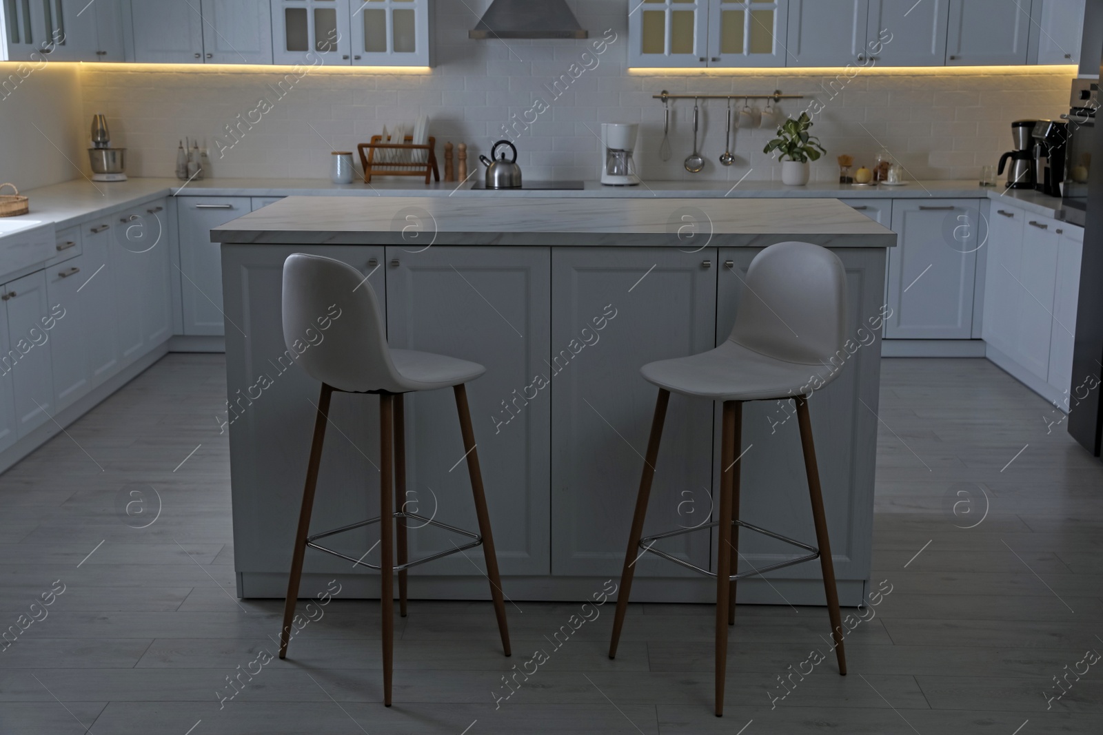 Photo of Modern kitchen interior with white marble table and stylish high chairs