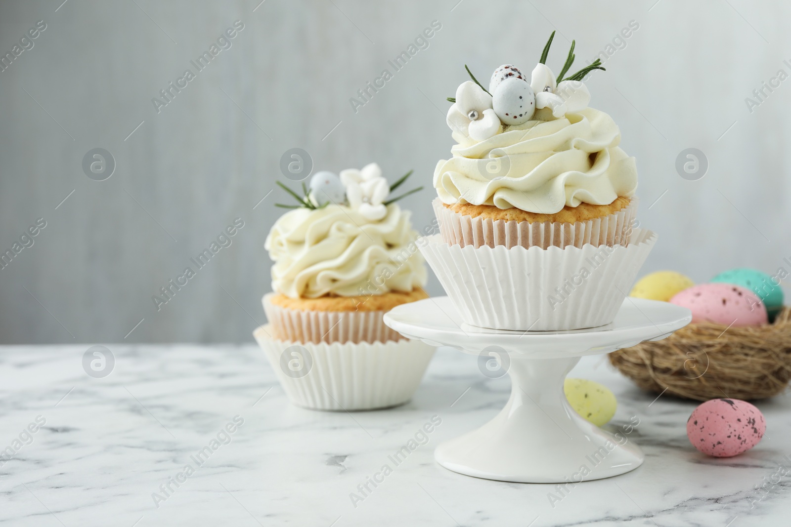 Photo of Tasty Easter cupcakes with vanilla cream on white marble table, space for text