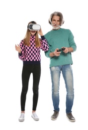 Photo of Teenage girl wearing VR headset and mature man with controller playing video games on white background