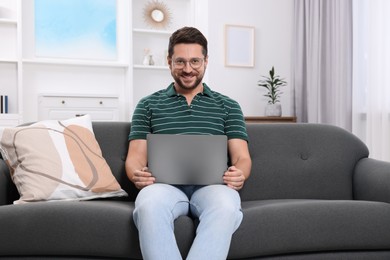 Photo of Happy man with laptop on sofa at home
