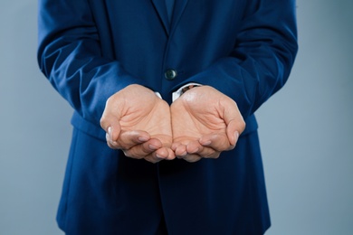 Photo of Businessman holding something on grey background, closeup of hands