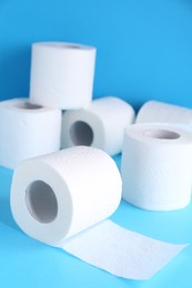 Photo of Soft toilet paper rolls on light blue background, closeup