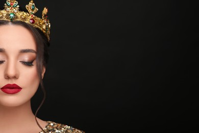 Photo of Beautiful young woman wearing luxurious crown on black background, closeup. Space for text