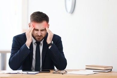 Man suffering from migraine at workplace in office