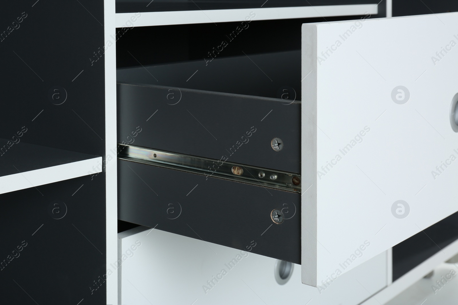 Photo of Stylish shelving unit with open drawer, closeup. Furniture for wardrobe room