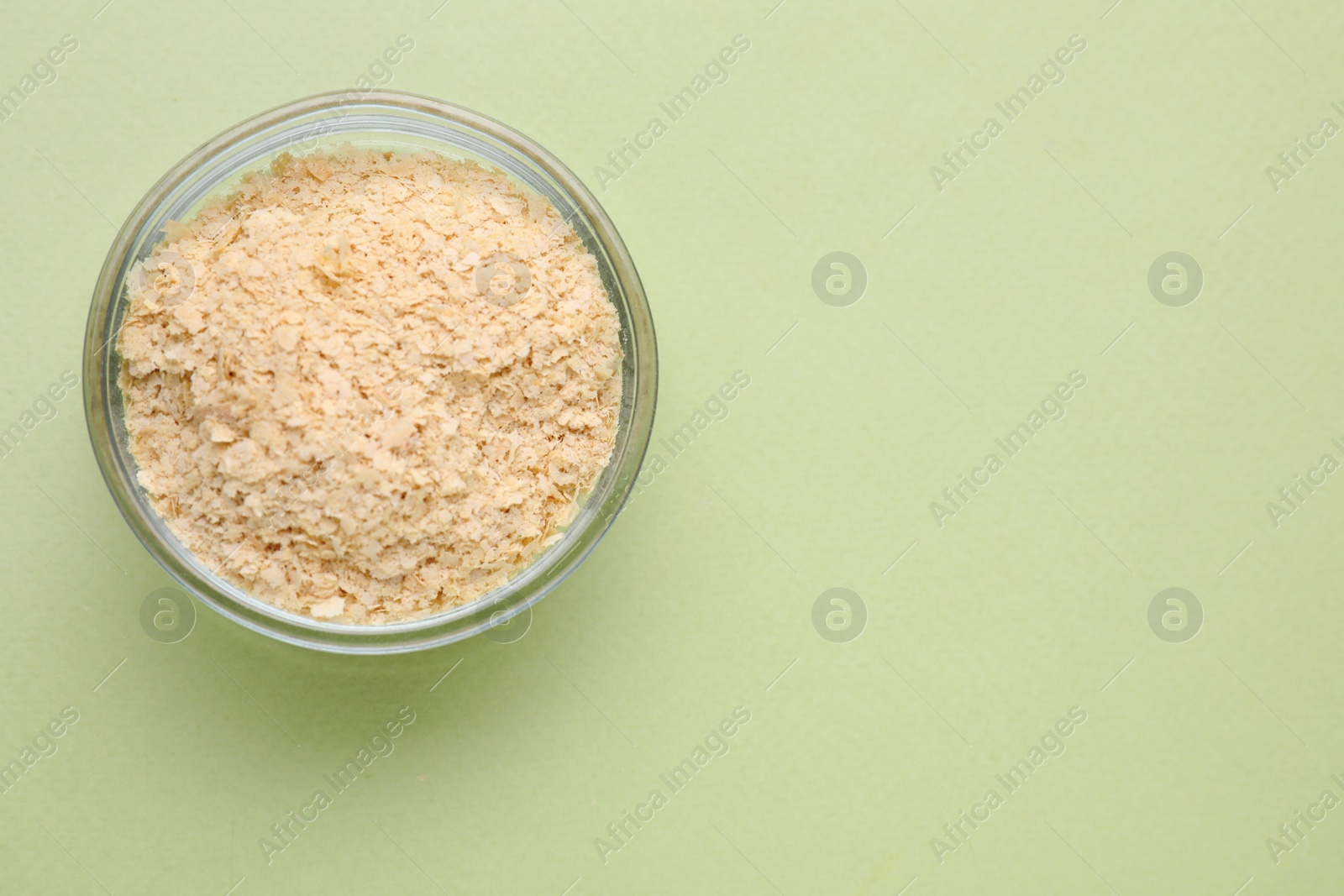 Photo of Beer yeast flakes on light green background, top view. Space for text