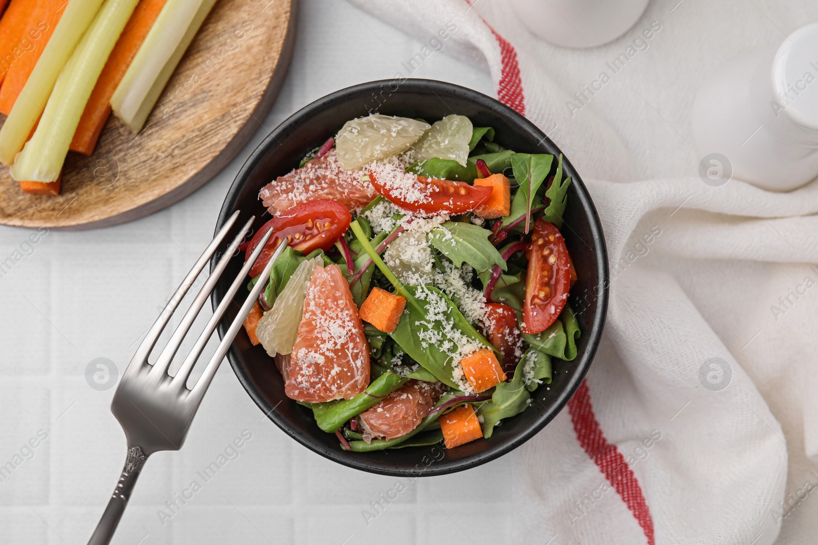 Photo of Delicious salad with pomelo, tomatoes and cheese on white tiled table, flat lay