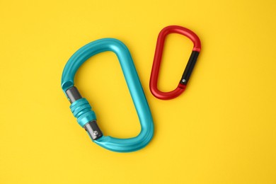 Photo of Two metal carabiners on yellow background, above view