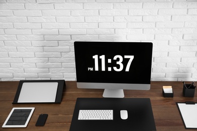 Modern workplace interior with computer and devices on table near brick wall