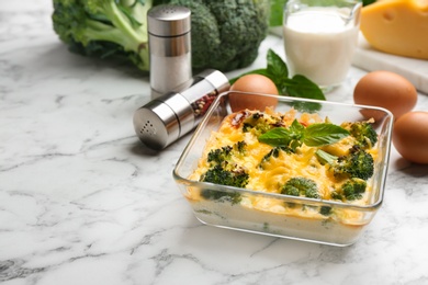 Photo of Tasty broccoli casserole in baking dish on white marble table