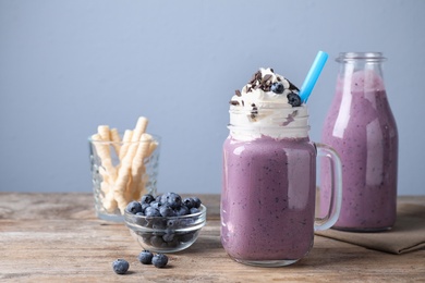 Photo of Tasty blueberry milk shake served on wooden table