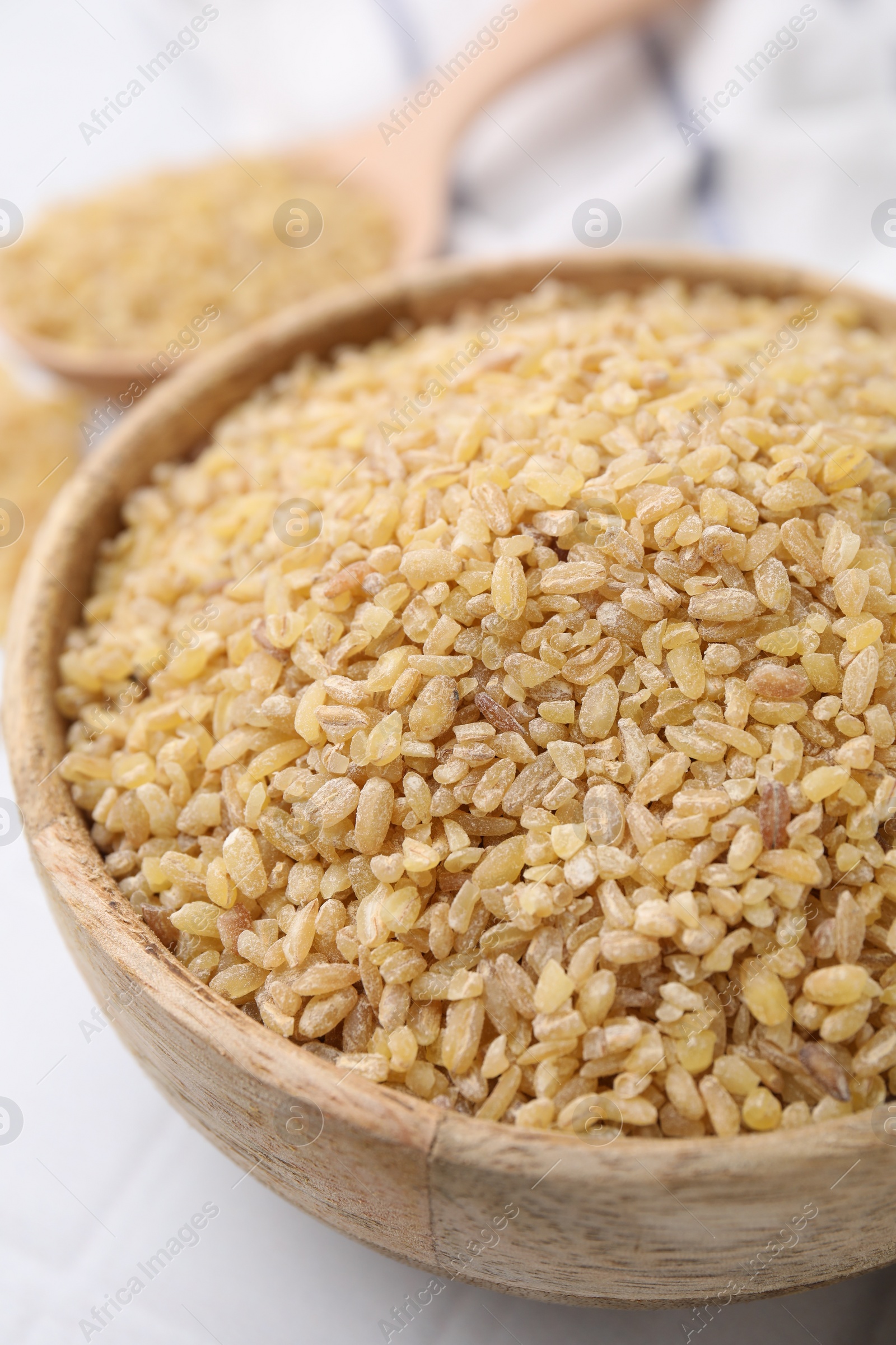 Photo of Raw bulgur in bowl on table, closeup