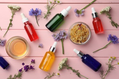 Photo of Aromatherapy. Different essential oils and flowers on pink wooden table, flat lay