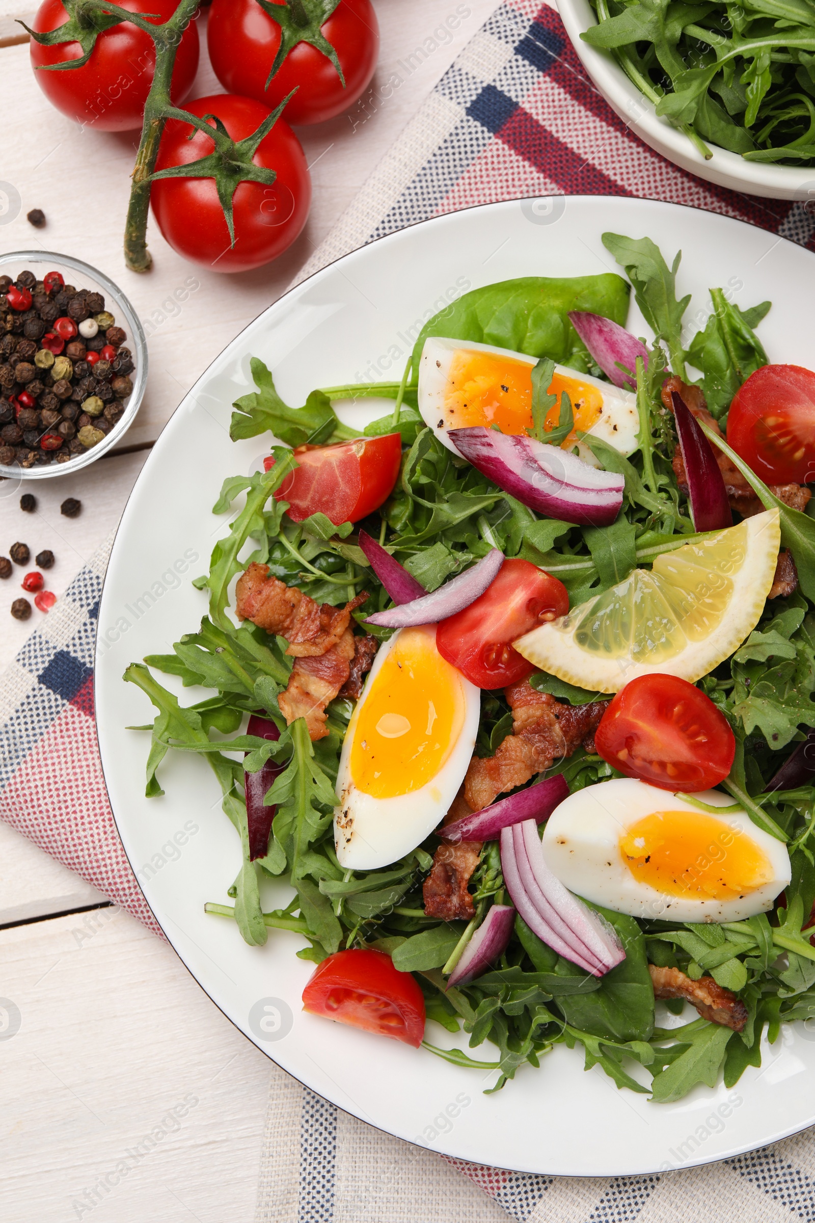 Photo of Delicious salad with boiled eggs, vegetables and bacon served on white wooden table, flat lay