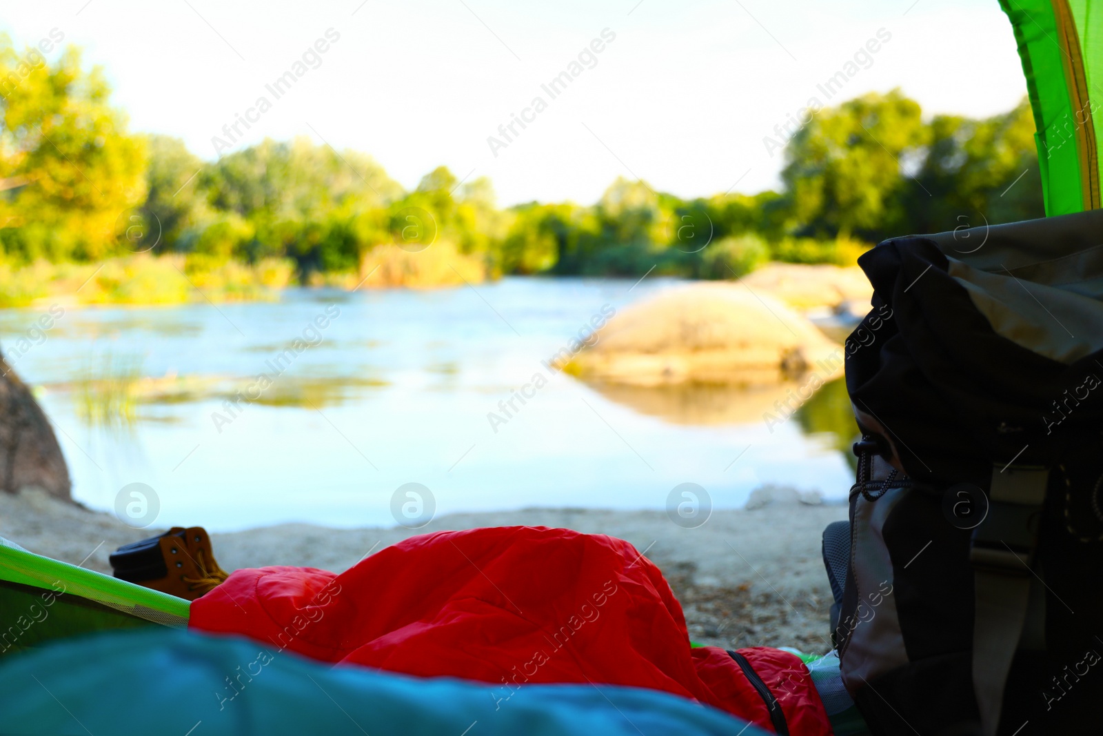 Photo of Camping tent with sleeping bag near lake, view from inside