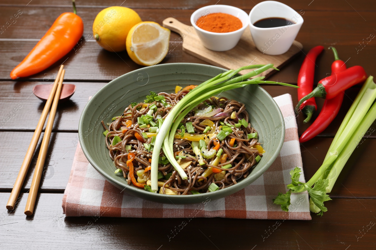 Photo of Stir-fry. Delicious cooked noodles with chicken and vegetables in bowl on wooden table