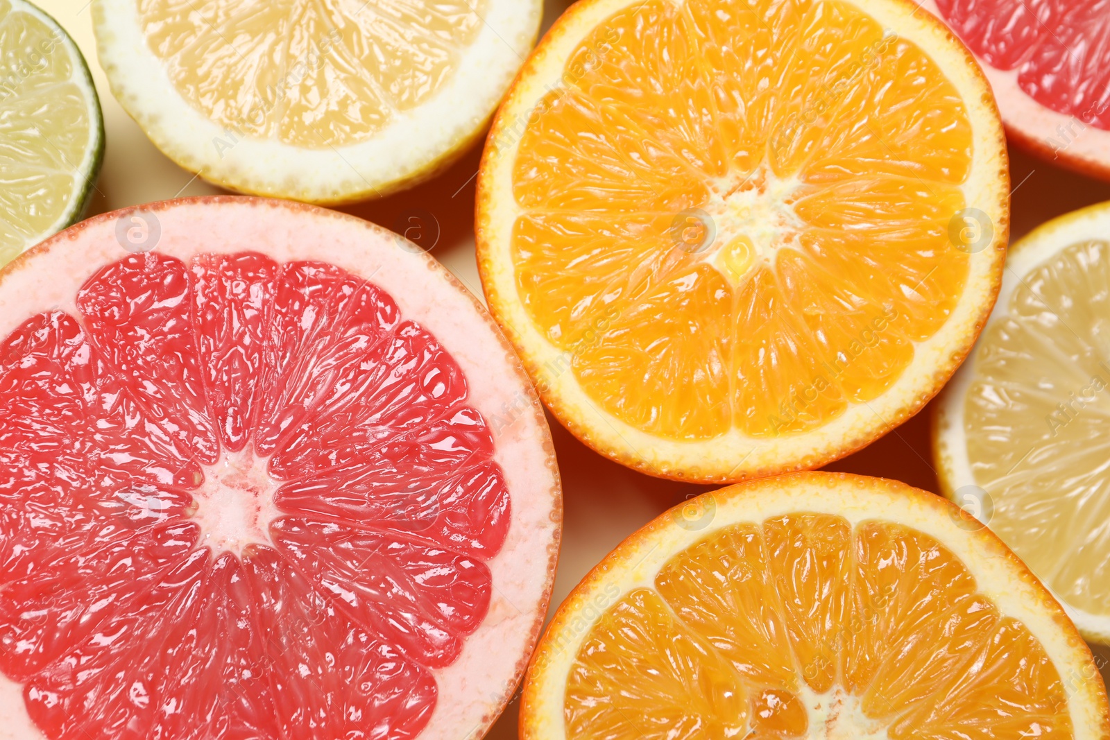 Photo of Different cut citrus fruits on beige table, flat lay