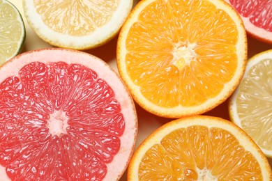 Different cut citrus fruits on beige table, flat lay