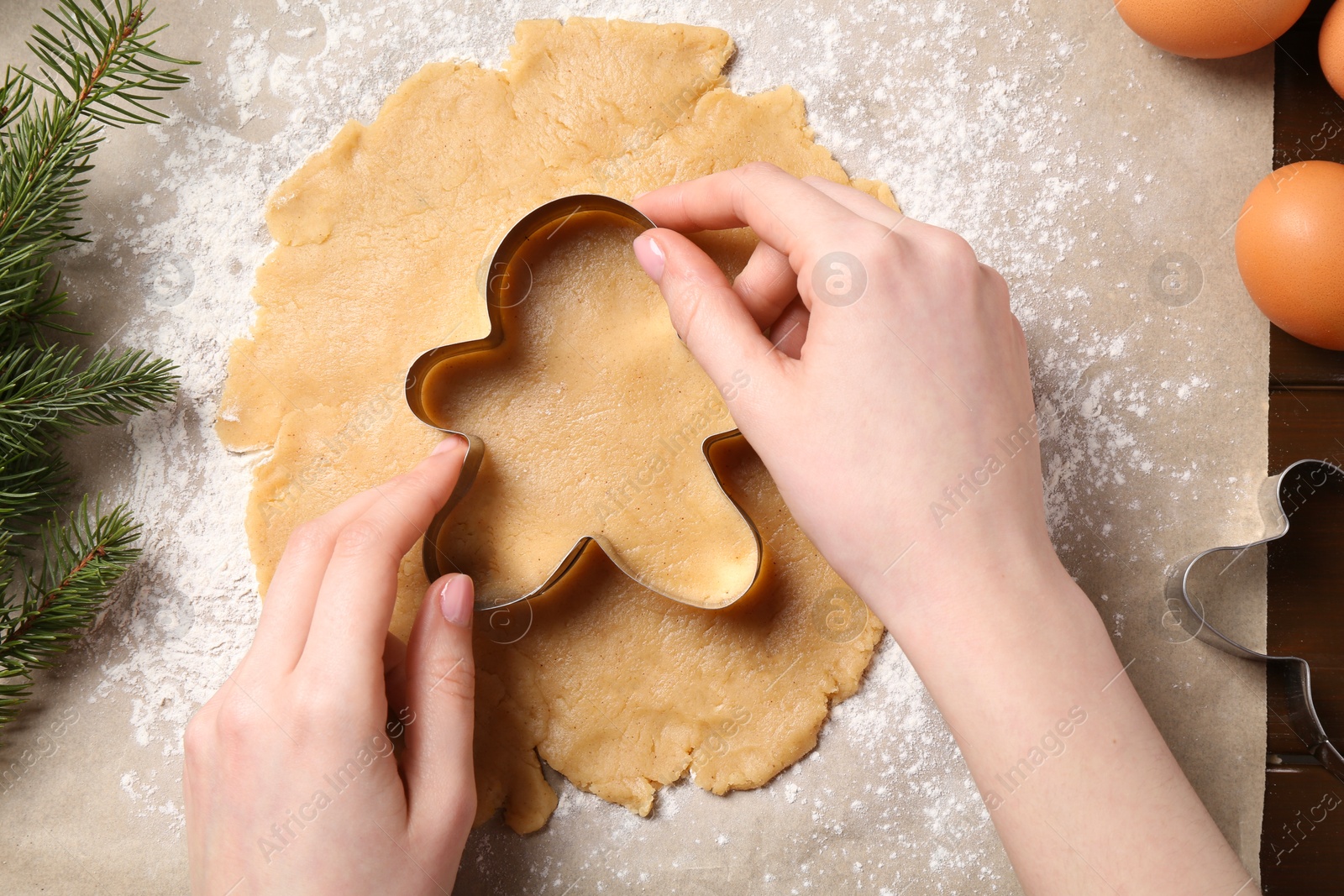 Photo of Woman making Christmas cookie with cutter at table, top view