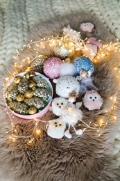 Photo of Beautiful Christmas tree baubles, toys and fairy lights on faux fur, above view