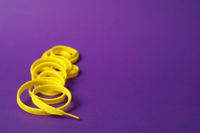 Yellow shoe lace on purple background. Space for text